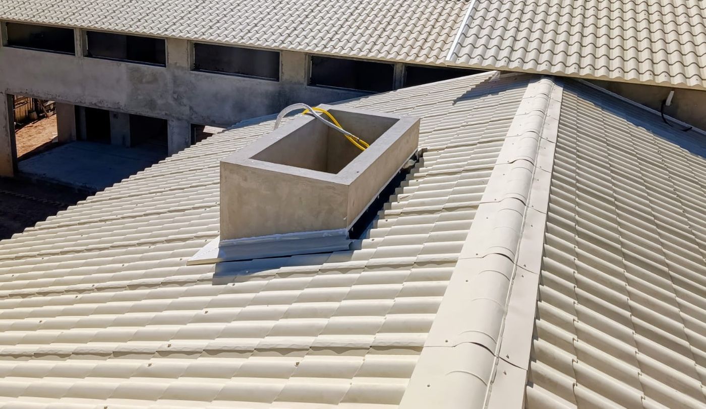 Vista ampla da cobertura com as claraboias das suítes e o anexo ao fundo.